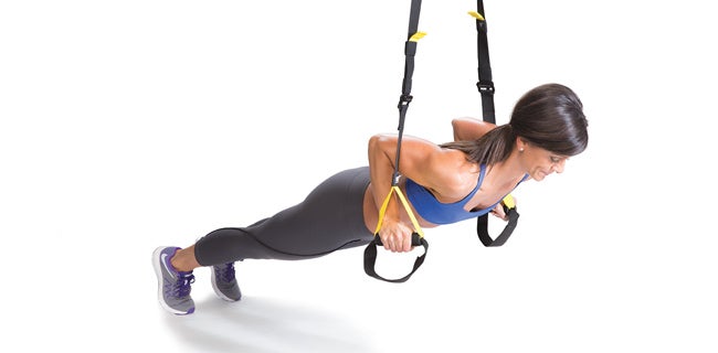 Women training arms with trx fitness straps in the gym doing push