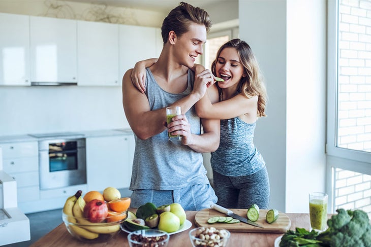 Meal Prep Snack Man and woman snacking on healthy food in kitchen
