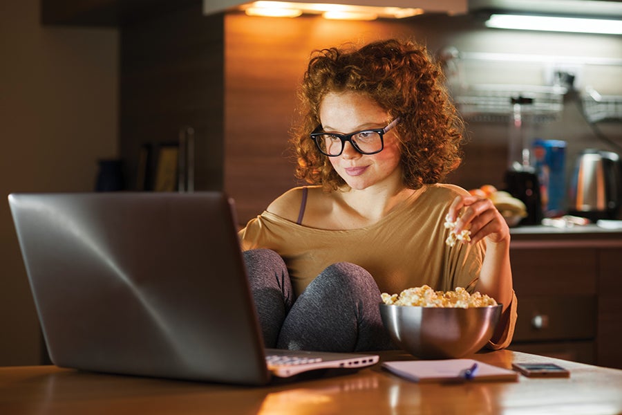 Woman snacking on popcorn while on her computer