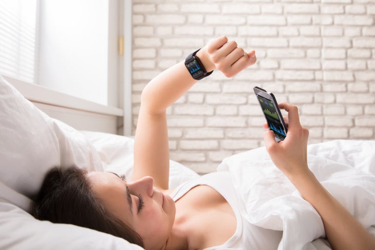 shutterstock_673634059 Woman on fitness tracker in bed