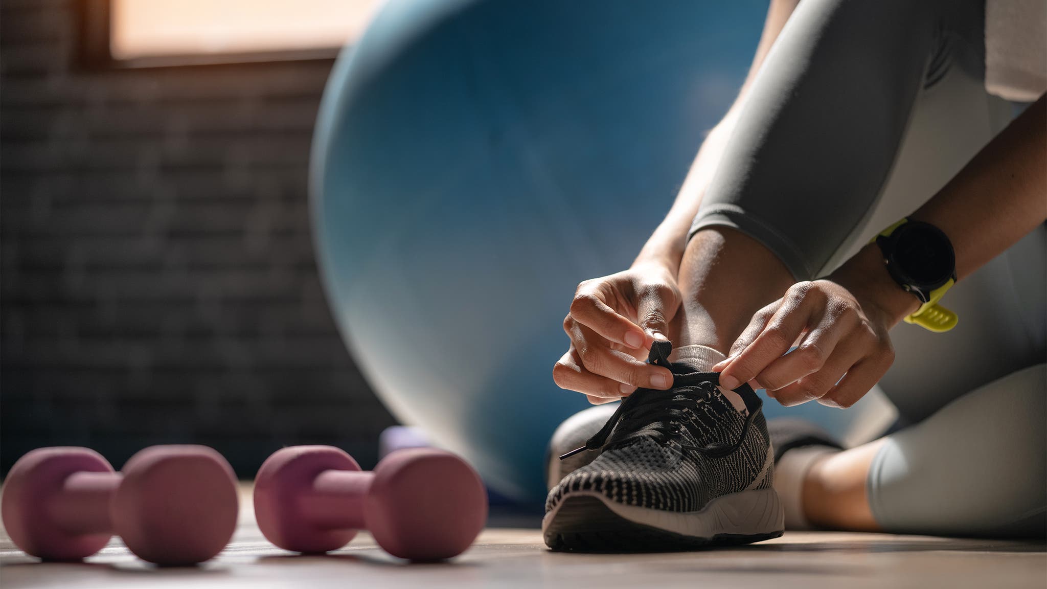 Woman Lacing Up her Shoes in the Gym
