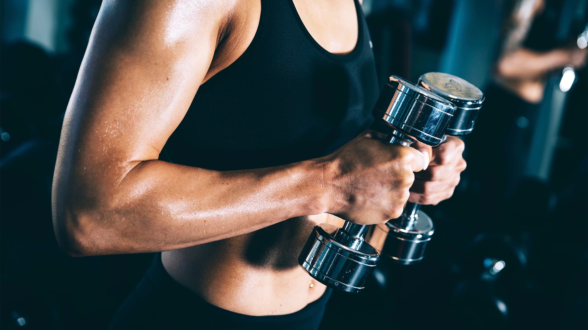 Woman lifting dumbbells - biceps curl