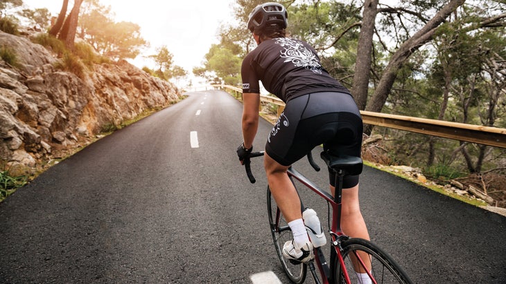 Woman cycling uphill outdoors.