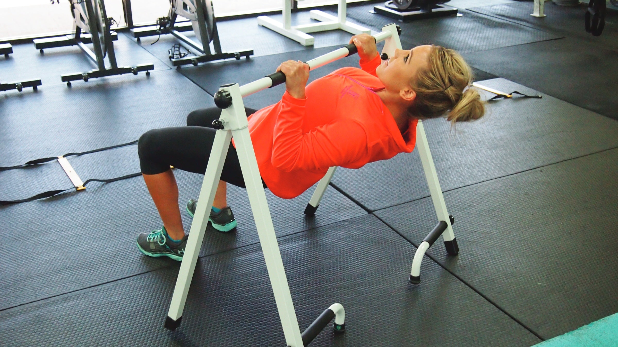 Woman using portable pull-up bar at the gym