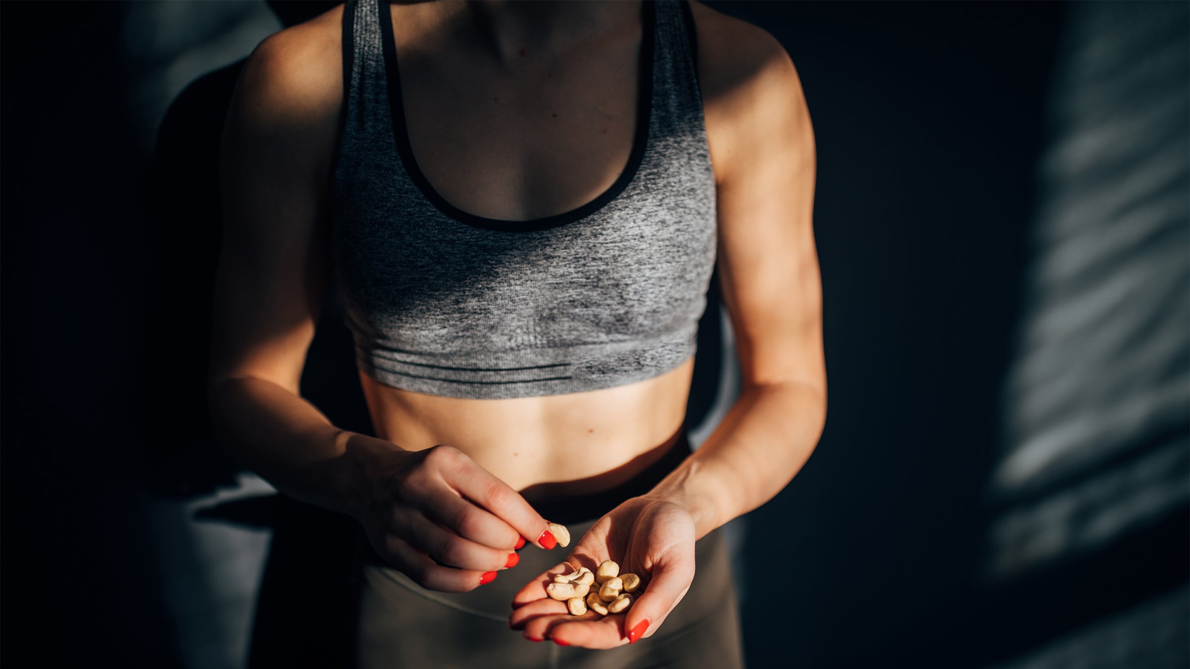 Woman eating a handful of nuts before or after a workout.